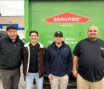 male employees in front of green truck